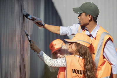 a man and a girl paint over some graffiti