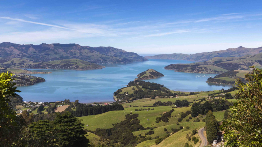 Coastal landscape with blue water, green hills, and small islands viewed from above.